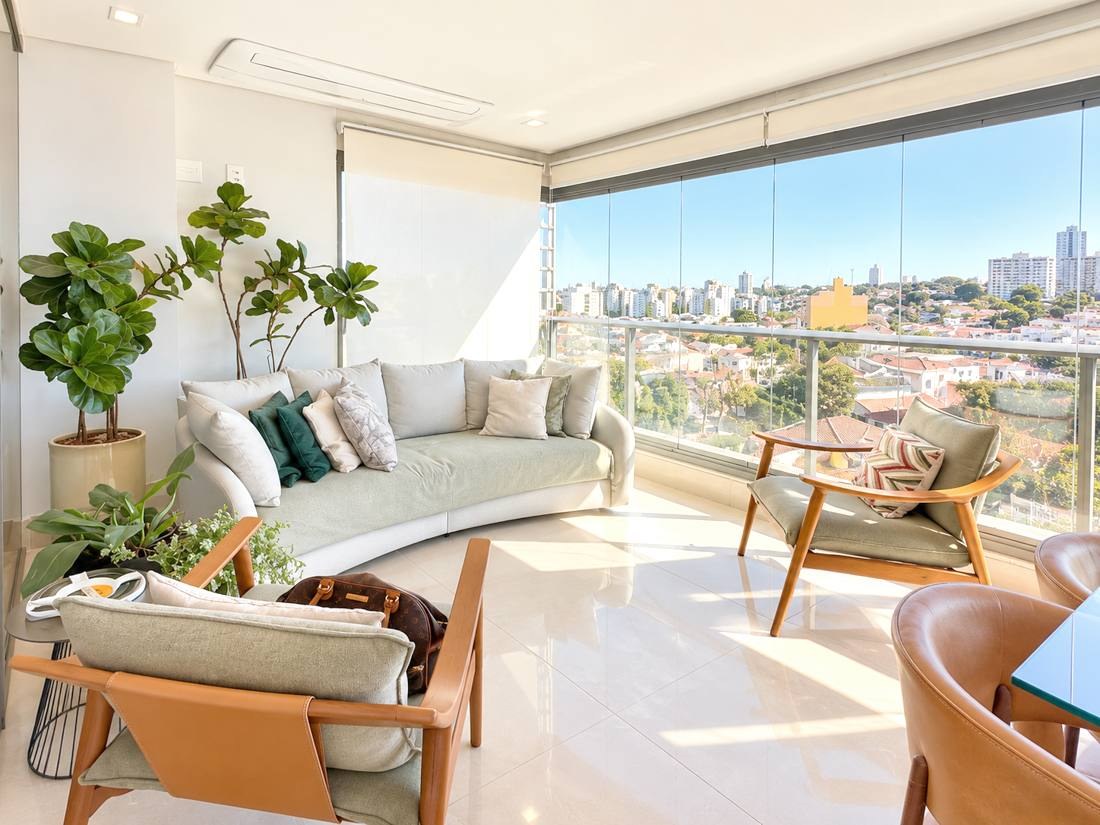 Varanda envidraçada com sofá, plantas e vista para a cidade